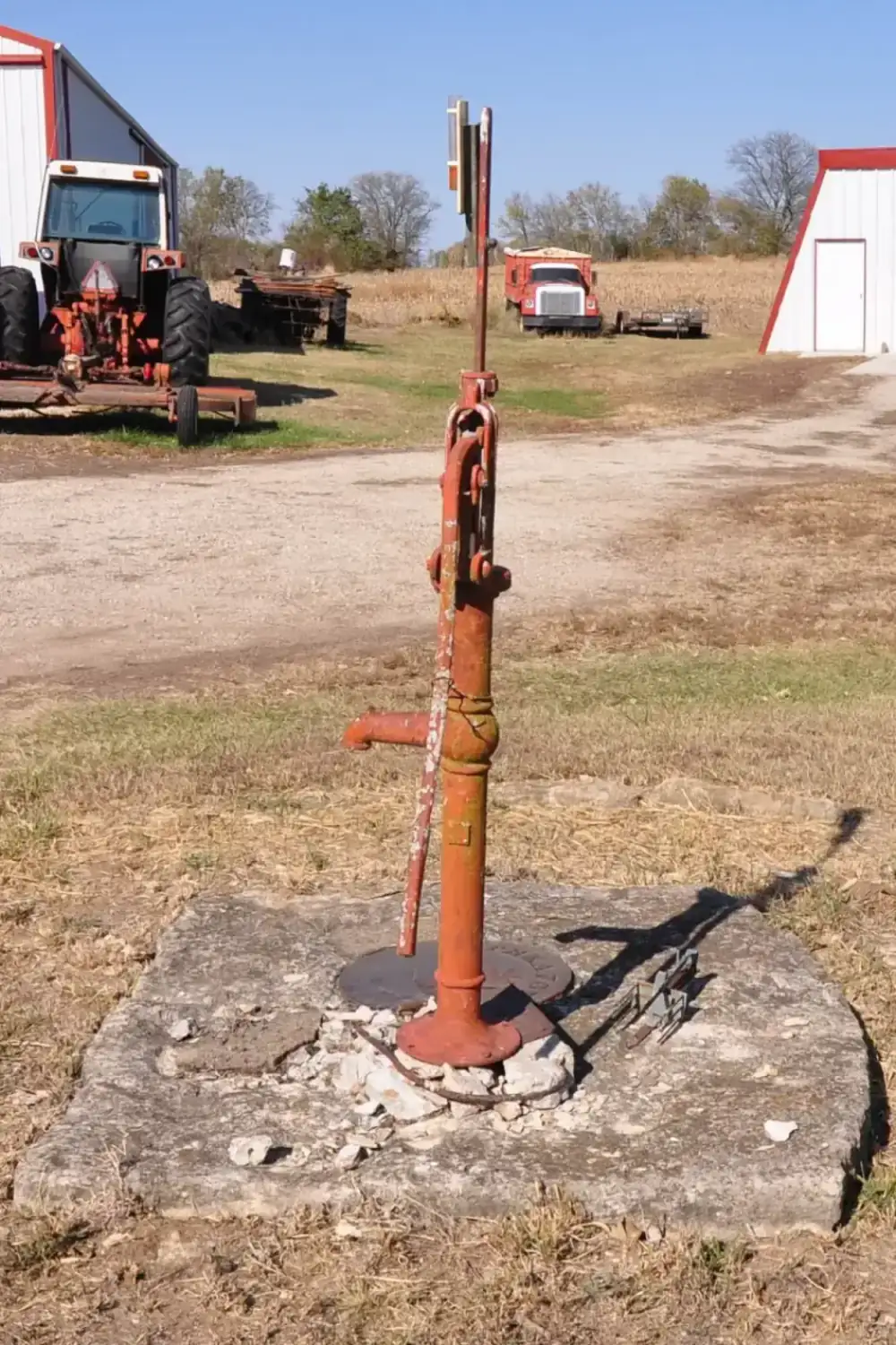 Old hand pump standing on a cracked concrete slab over a disused water well, the kind of well that needs plugging in El Paso County TX