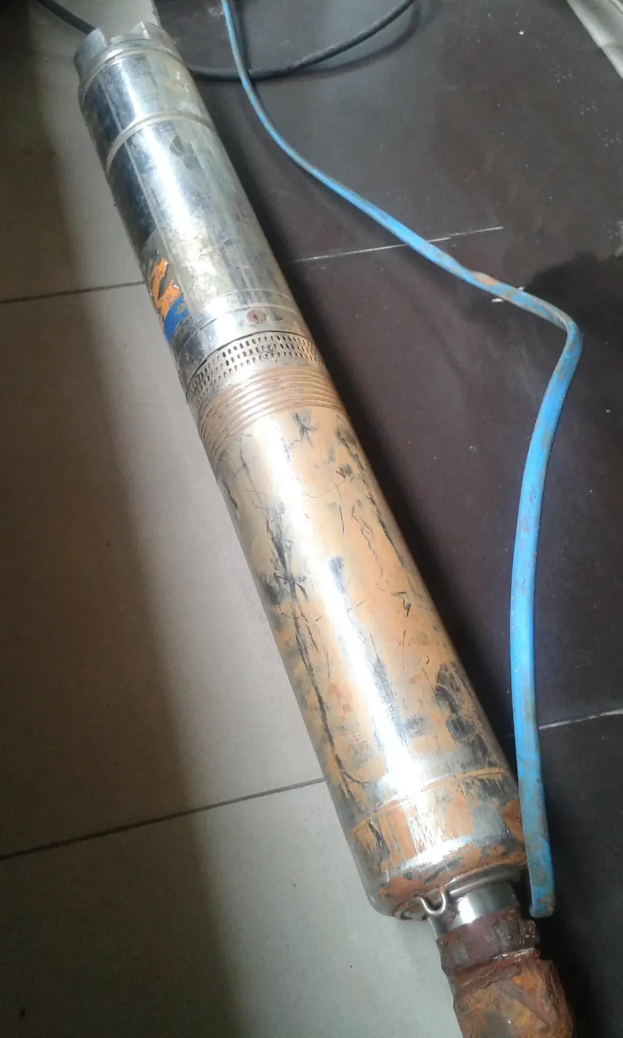 Stainless submersible well pump and its drop cable laid out after being pulled from a well casing